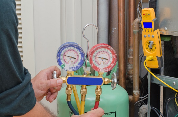 technician adjusting hvac gauges in front of green tank technician adjusting hvac gauges in front of green tank